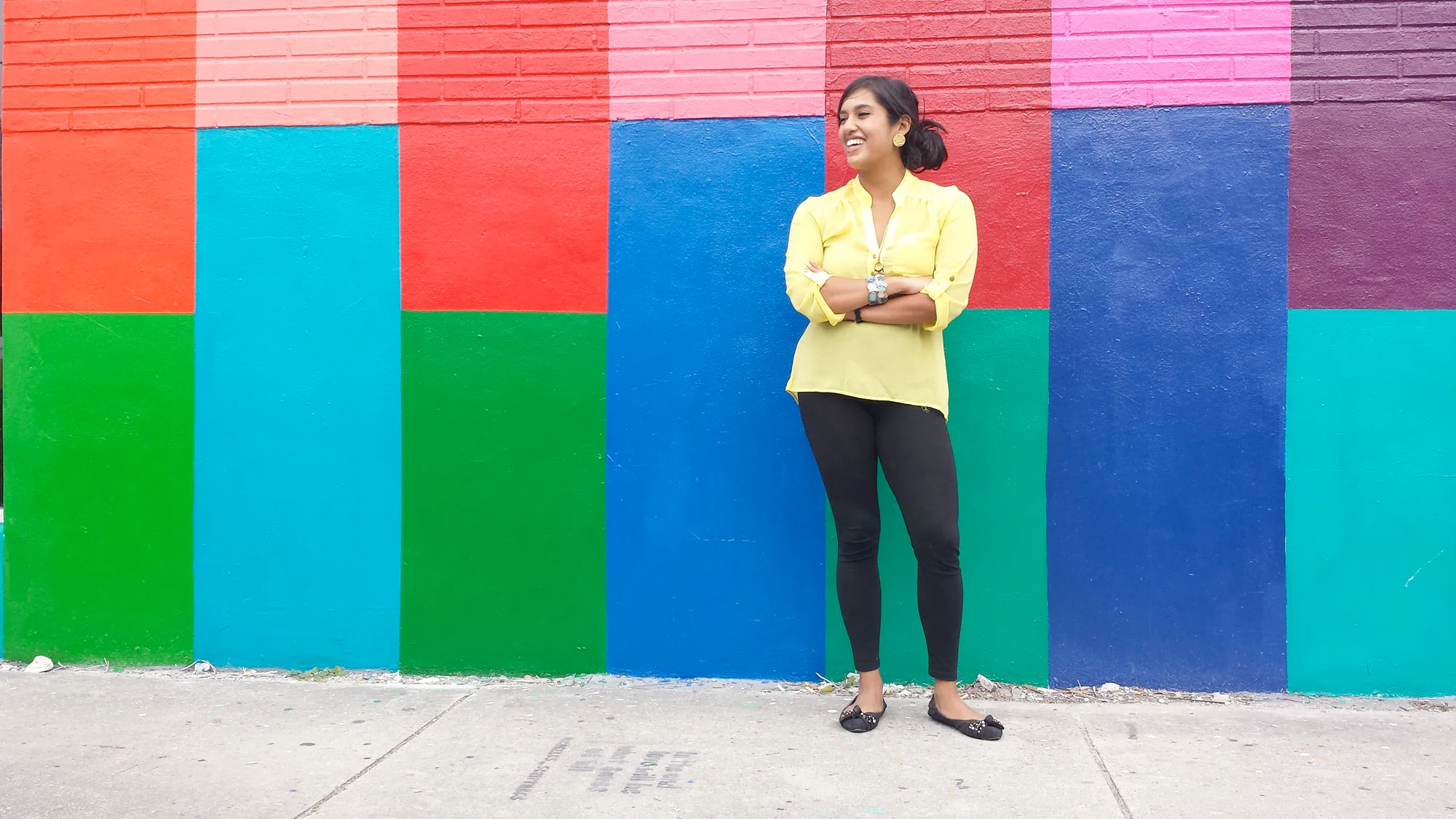 Jareen Imam standing in front of a colorful painted wall
